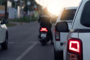 Rear side of white pickup car on the aspahlt road. Transtport of car turn on brake light in the business time environment of moring time. Traffic congestion and queues of cars. photo