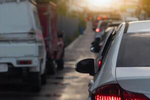 Rear side of white car on the aspahlt road. Transtport of car turn on brake light in the business time environment of moring time. Traffic congestion and queues of cars on wet road. photo