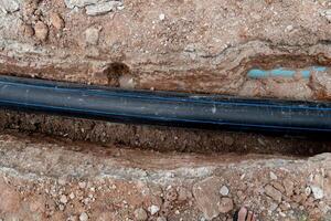 Pipe of High-Density Polyethylene. Placed in a long line along the excavation line. photo
