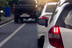 Rear side view of white car on the aspahlt road. Transtport of car turn on brake light in the business time environment of moring time. Traffic congestion and queues of cars. photo
