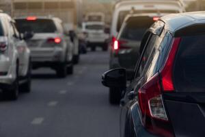 Rear side of black car on the aspahlt road. Transtport of car turn on brake light in the business time environment of moring time. Traffic congestion and queues of cars. photo