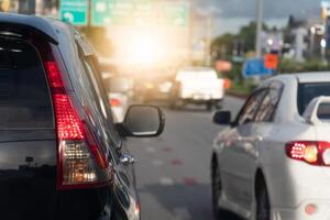 Rear side of black car on the aspahlt road. Transtport of car turn on brake light in the business time environment of moring time. Traffic congestion and queues of cars. photo