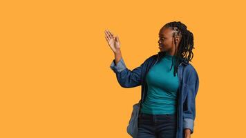 African american woman pointing upwards with finger doing recommendation, talking with audience. Girl doing presentation, showing copy text, isolated over studio background, camera B photo