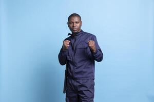Professional security agent poses with clenched fists in studio, on protection duty ready for a fight in order to safeguard something. Armed guard with proper combat and defense training. photo