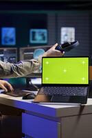Focus on green screen laptop used by developer updating artificial intelligence machine learning algorithm. Close up shot of mockup notebook used by IT expert programming AI photo