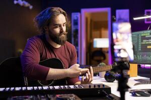 Guitarist instructor recording online music lesson on smartphone app and explaining all musical notes, solo performance. Composer providing explanations of the theory behind each string on instrument. photo