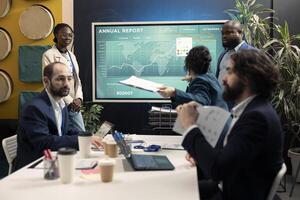 Staff members reviewing trends helping in making decisions to corelate with business goals. Forecast associates working together to meet project deadline, examine organizational data. photo