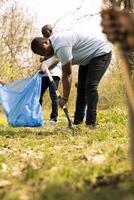 Diverse people using claw tools to grab garbage and plastic, storing it in trash disposal bags. Volunteers group gathering to collect rubbish and recycling waste for sustainable lifestyle. photo