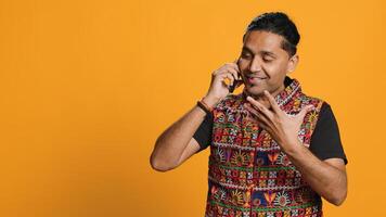 Irked indian man fighting with friends during telephone call, isolated over studio background. Outraged person arguing with mates during conversation on mobile phone, camera A photo