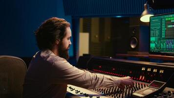 Portrait of music producer working in control room professional studio and editing audio recordings, mixing console and daw software in soundproof space. Sound engineer in post production. Camera B. photo