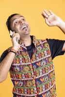 Joyous man chuckling after hearing amusing jokes from best friend over telephone call using smartphone. Person talking with humorous mate in phone call using phone, having fun, studio backdrop photo