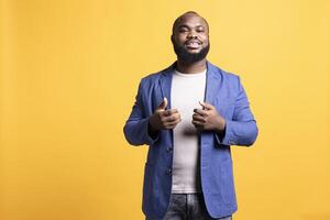 Portrait of cool and collected african american man exuding self assurance, isolated over yellow studio background. Expressive BIPOC person looking dapper, posing nonchalantly photo