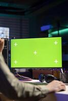 Man using isolated screen PC monitor to update artificial intelligence neural networks, writing binary code script. IT professional upgrading high tech AI using chroma key computer, close up photo