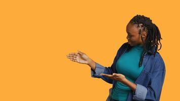 African american woman pointing upwards with finger doing recommendation, talking with audience. Girl doing presentation, showing copy text, isolated over studio background, camera A photo
