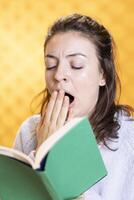 Exhausted woman yawning while reading uninteresting book needed for school exam, studio background. Tired student yearning for sleep while learning from academic textbook, close up shot photo