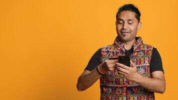 Man adding payment method on phone website, delighted to take advantage of promotions, studio background. Person thrilled to do internet shopping, typing credit card data on smartphone, camera A photo