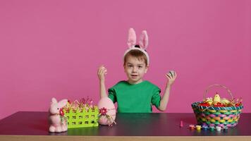 Smiling cute kid playing peek a boo game with painted colorful eggs, having fun with easter decorations and arrangements on camera. Enthusiastic joyful boy being excited about holiday. Camera B. photo