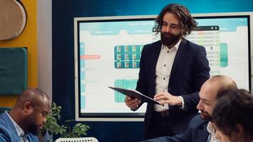 Team leader sharing clipboards with the latest performance metrics to discuss about work efficiency and optimization during corporate briefing meeting. Manager is consulting his personnel. Camera A. photo