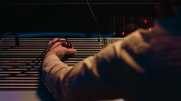 Music producer fixing coiled cable inside amplifier or audio compressor, prepares control room technical equipment for a recording session. Sound engineer works on producing tracks. Camera A. photo
