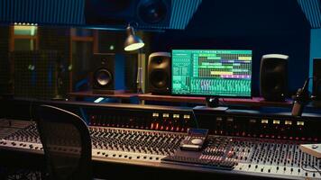 Music recording studio control room with daw software used to mix and master audio tracks, empty soundproof professional space. Modern sliders on control panel board to edit sound waves. photo