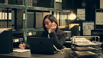 Private agent calls forensic experts on landline phone in archive, schedules meetings with witnesses to gather information or insights. Detective conducting criminal investigation. Camera A. photo