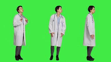 General practitioner waiting for patients to attend checkup appointments, feeling impatient against greenscreen backdrop. Woman physician with white coat waits for people, confident medic. Camera A. photo