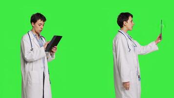 General practitioner browsing online sites and waving on videocall, using a tablet for multiple actions on the internet. Woman medic navigates on web and attends videoconference exam. Camera B. photo