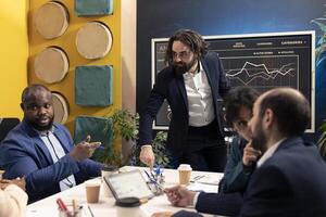 Business colleagues evaluating performance and success metrics within the organization, presenting project details. Coworkers measuring infographics and reports, team efficiency and progress. photo