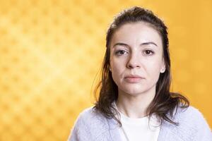 Portrait of optimistic woman posing, feeling happy and relaxed, isolated over yellow studio background. Close up shot of lively radiant caucasian lady standing, looking at camera photo