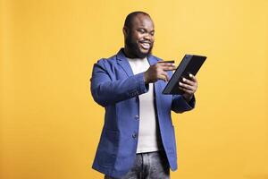 Jolly man adding payment method on website, enjoying himself, isolated over studio background. Happy man excited to do internet shopping, carefully typing credit card information photo