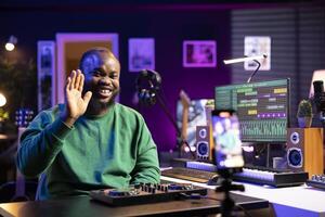 Sound technician instructor hosting an online master class to teach people how to use a mixing console in post production. Using motorized faders and pre amp knobs for a demonstration. photo