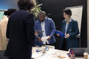 Business partners reviewing latest budgeting plans on papers, organizing a briefing meeting to share ideas and details about updates to ensure progress. Colleagues making decisions for a project. photo