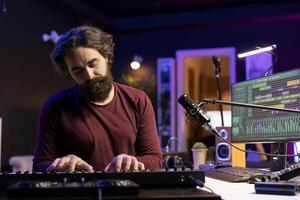 Audio engineer playing electronic keyboard and recording tunes, using mixing console and midi controller to create new music. Artist songwriter uses stereo tools and synthesizer at home studio. photo