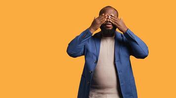 African american man covering eyes, ears and mouth with hands, imitating the three wise monkeys. BIPOC person doing dont see, dont hear and dont speak gesturing concept, studio background, camera B photo