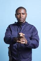 African american agent pointing an imaginary pistol in front of the camera, mimicking target shooting practice. Portrait of security guard holds his hand in the shape of a firearm. photo