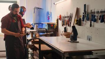 Woodworker using bench vise to hold lumber block, starting furniture assembling in workshop. Craftsperson in joinery using vice tool to clamp piece of wood before carving it, camera B photo