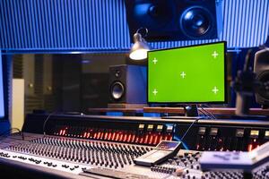 Empty professional studio control room with greenscreen pc, technical equipment and panel board used for mixing and mastering tracks. Equalizer and buttons on control desk producing music. photo
