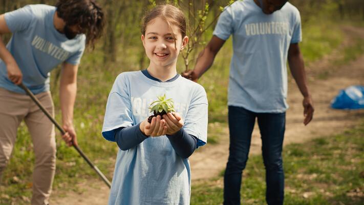 Cute child activist presenting a small seedling tree in her hands, fighting to protect the environment and natural ecosystem. Little girl working to conserve nature and plant trees. Camera A.