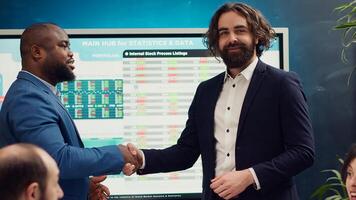 Business partners are shaking hands after establishing a new project between their enterprises. Two managers starting a collaboration to expand organization and increase finances. Camera A. photo