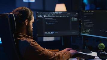 Computer scientist developing code on PC while in apartment office using java programming languages. IT admin brainstorming ways of fixing database errors while working from home, camera A photo