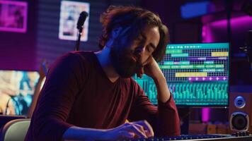 Songwriter getting upset after hearing wrong piano notes, trying to compose a song using midi controller electronic keyboard. Musician playing instrument keys to create the perfect sound. Camera A. photo