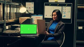 Private inspector examining legal documents and uses greenscreen on laptop, working on crime investigation in incident room. Law agent reads files, isolated copyspace mockup layout. Camera A. photo