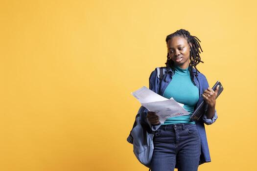 BIPOC woman browsing though marketing report pages, studio background. African american office clerk reading documents containing economic graphs and figures, solving business tasks photo
