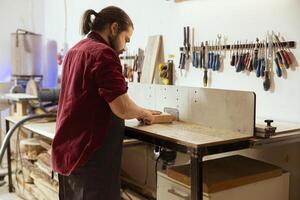 Skilled carpenter meticulously operating wood shaper in assembly shop, creating intricate designs with precision. Cabinetmaker uses spindle moulder to shape and mold wooden pieces photo