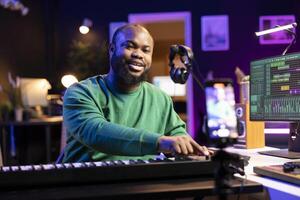 Musician doing online paid classes to help people play piano notes, teaching lessons from his home studio and recording tutorials. Musical instructor playing midi controller keyboard. photo