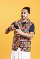 Man looking at credit card to read banking account needed for doing online purchases during sales period. Person wearing traditional indian attire does internet shopping using cellphone photo