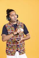 Joyous man enjoying fresh coffee, chatting with mates, listening music. Happy person using mobile phone while drinking caffeinated beverage, hearing songs, studio backdrop photo