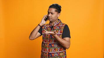 Indian man discussing with best friend over telephone call using smartphone. Cheerful person talking with mate in phone call using cellphone, isolated over studio background, camera B photo