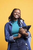 Portrait of smiling BIPOC woman holding laptop, preparing to start work shift, isolated over studio background. Grinning worker with notebook ready to do business related tasks on it photo