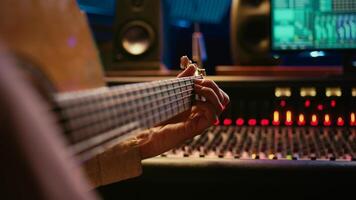 Skilled artist singing on his guitar and recording tunes for a future song, working on new album in control room at studio. Musician composer creating a new track on instrument. Camera B. photo